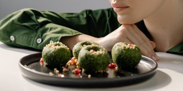 Close-up of spinach pkhali, a Georgian vegan dish, with a woman in green observing.